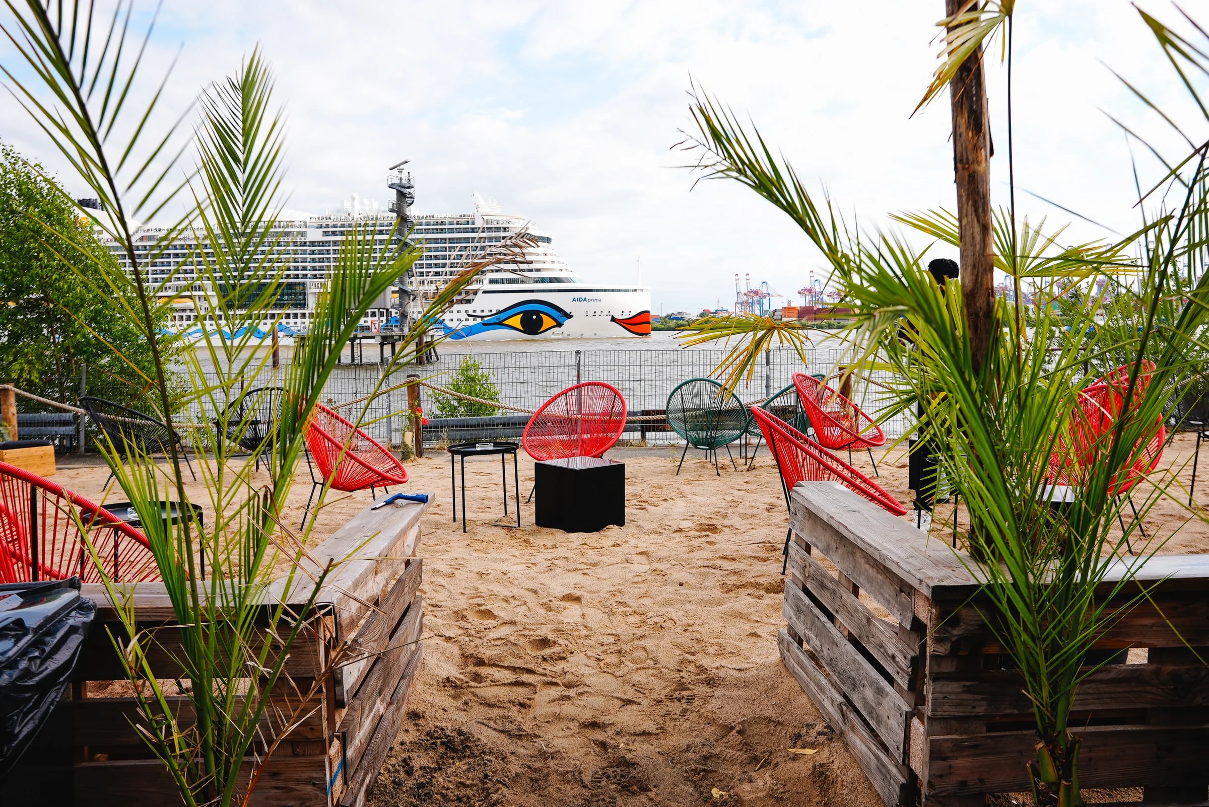 Lounge mit roten Sesseln und Palmen direkt an der Elbe